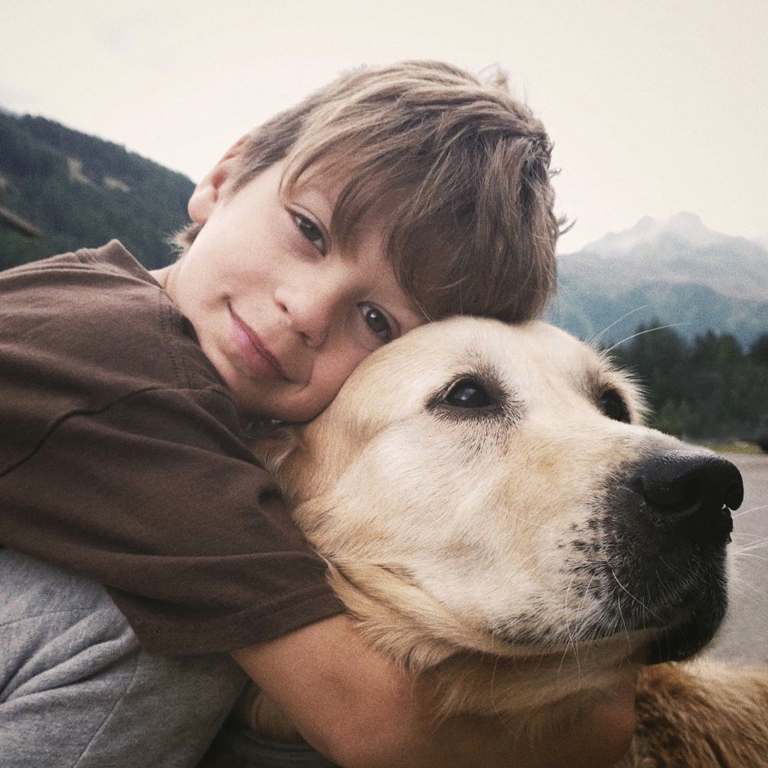 Smiling child hugging golden retriever outdoors, promoting dog health and natural supplements