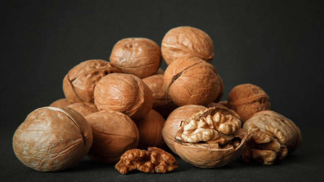 Whole and cracked walnuts on a dark background