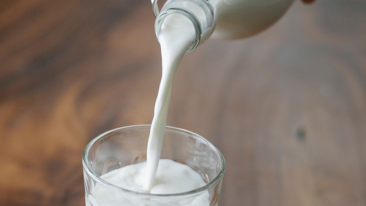 Milk being poured into a glass on a wooden table