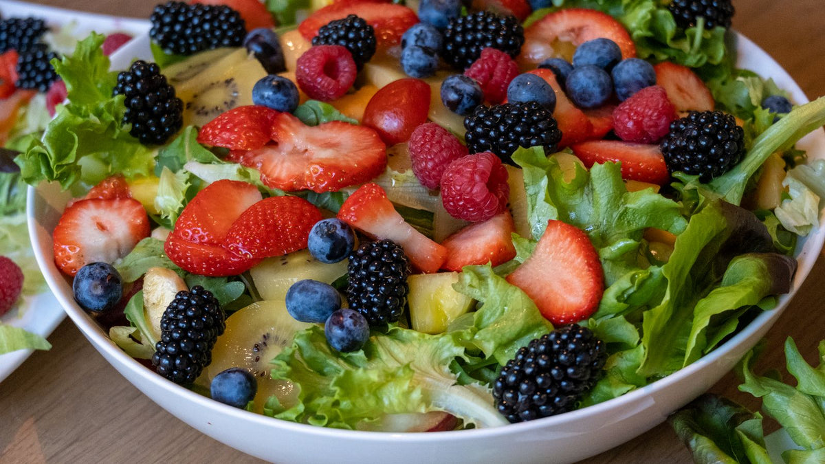 A bowl of assorted fresh fruit including strawberries, kiwi and berries, safe fruits dogs can eat