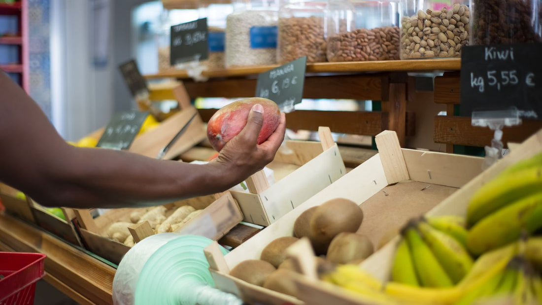 Person choosing a fresh mango at a market